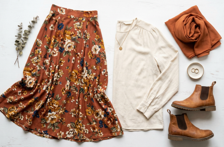 How to Wear Long Skirts Without Looking Frumpy: Style Tips for Every Body Type Modest outfit flat lay featuring a rust floral maxi skirt, long sleeve cream blouse, ankle boots and a terracotta hijab scarf on a white background
